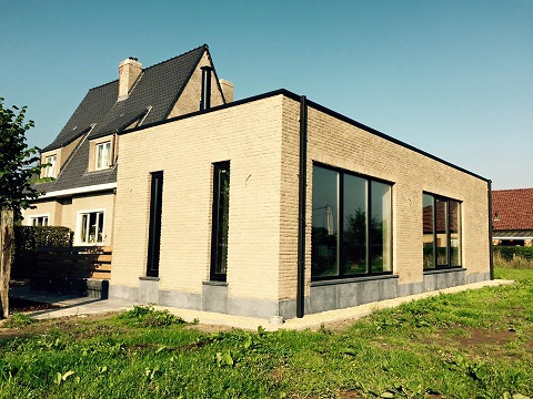 Houtskelet aanbouw met plat dak naast moderne woning. De aanbouw is afgewerkt met gevelsteen.