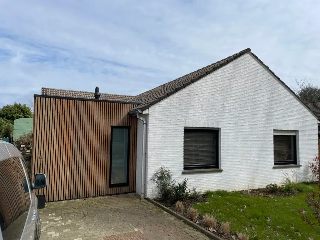 Woning in Beersel vóór de optopping, met witte bakstenen gevel en houten aanbouw
