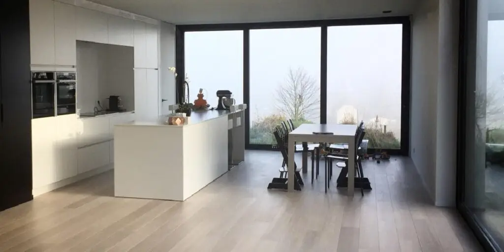 Keuken met kookeiland en eetruimte aan grote ramen in de woning in Dilbeek