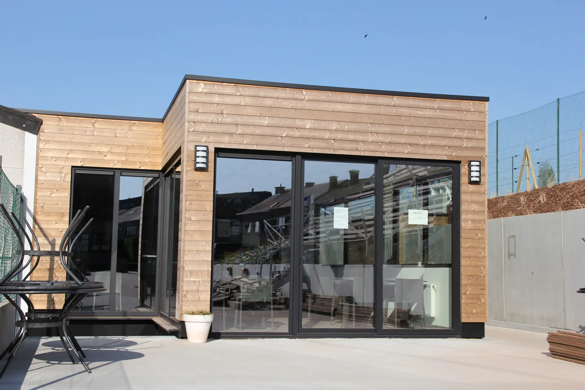 Ingang van het nieuwe clubhuis van TC Zottegem en Padel Zottegem met houten gevelbekleding en glazen deuren