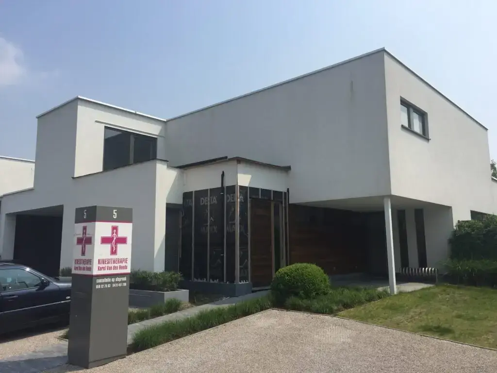 Buitenaanzicht van de woning met de aanbouw en grote ramen in Waregem