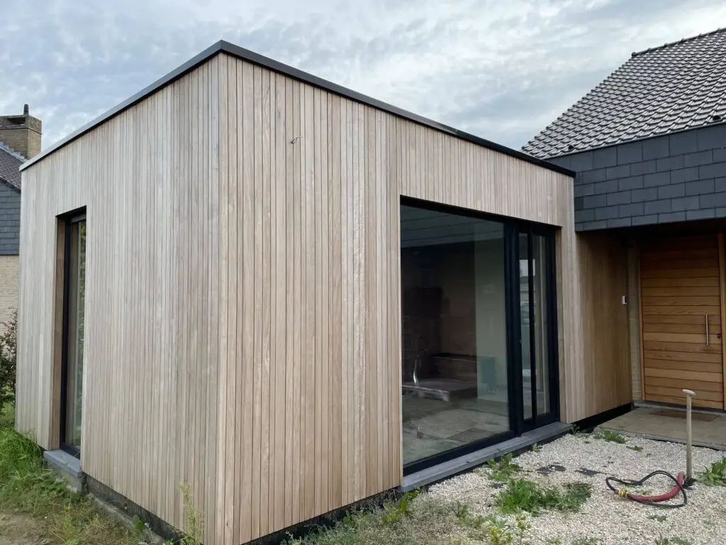 Aanbouw met verticale houten gevelbekleding en een breed schuifraam
