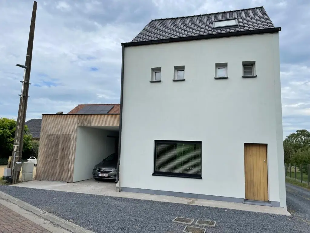 Witte crepi voorgevel met houten carport naast de woning in Semmerzake