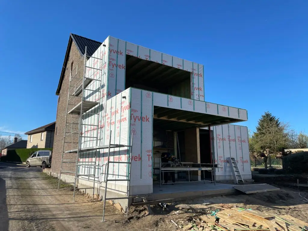 Houtskelet aanbouw op twee niveaus met beschermfolie en open raamvlakken in Semmerzake