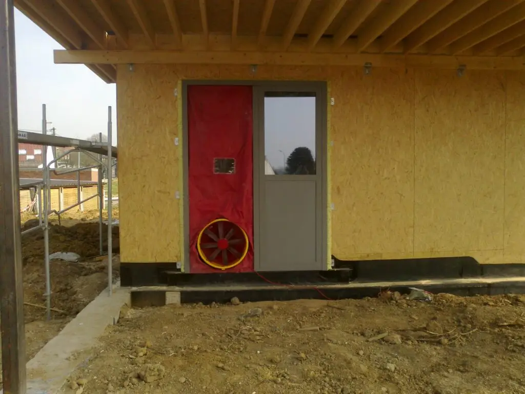 Rood testdoek en ventilator in de deur van de houtskeletwoning in Ophasselt