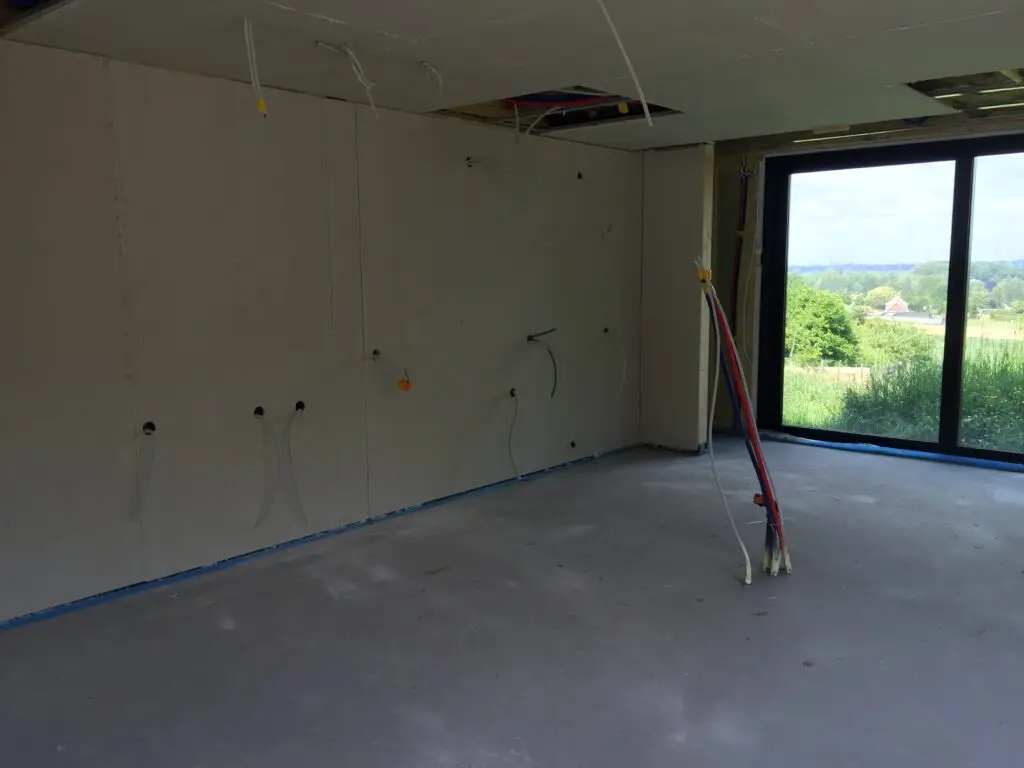 Binnenruimte met wandplaten, plafondplaten en groot raam tijdens de afwerking in Dilbeek