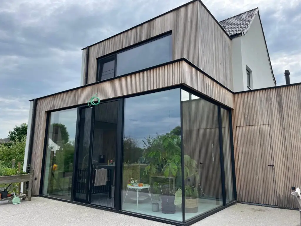 Thermo fraké gevelbekleding en glazen hoek van de houtskelet aanbouw in Semmerzake