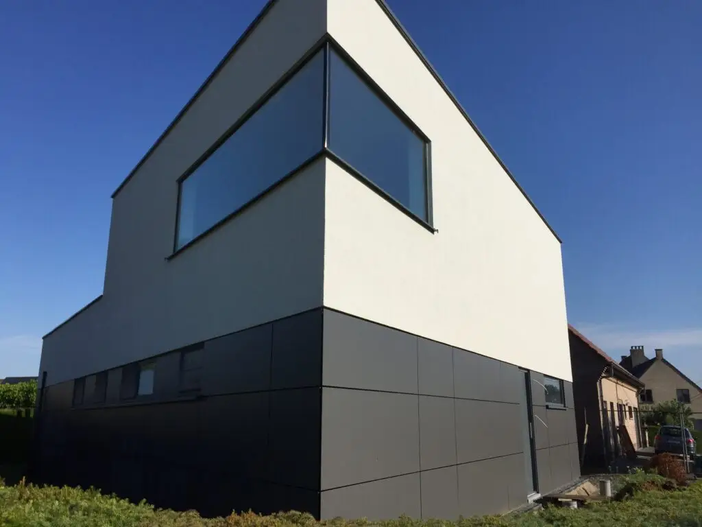 Afgewerkte nieuwbouw in Zottegem met Trespa-panelen beneden, lichte crepi boven en een hoekraam