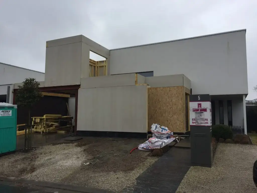 Houten aanbouw met plaatbekleding naast de bestaande woning in Waregem
