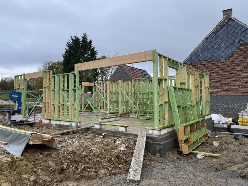 Houtskeletwanden in opbouw naast een bestaande bakstenen gevel in Brakel