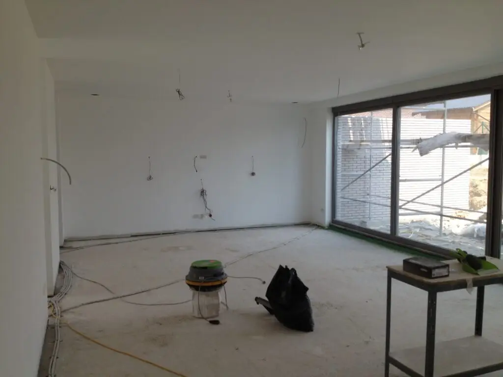Witte binnenwanden en brede schuiframen tijdens de afwerking in Ophasselt