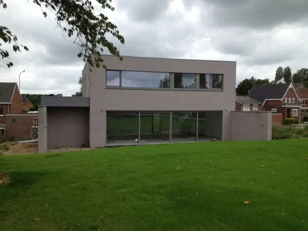 Tuingevel met lichte gevelsteen en brede ramen van de woning in Ophasselt