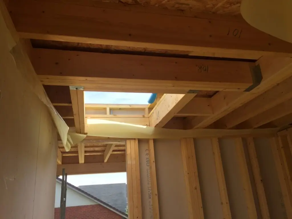 Constructie van het platte dak met houten balken bij de optopping in Koksijde