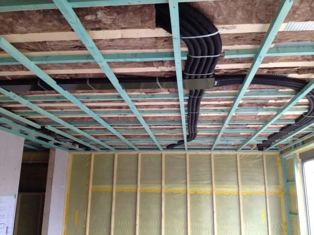 Zwarte leidingen en houten lattenwerk onder het plafond in Ophasselt
