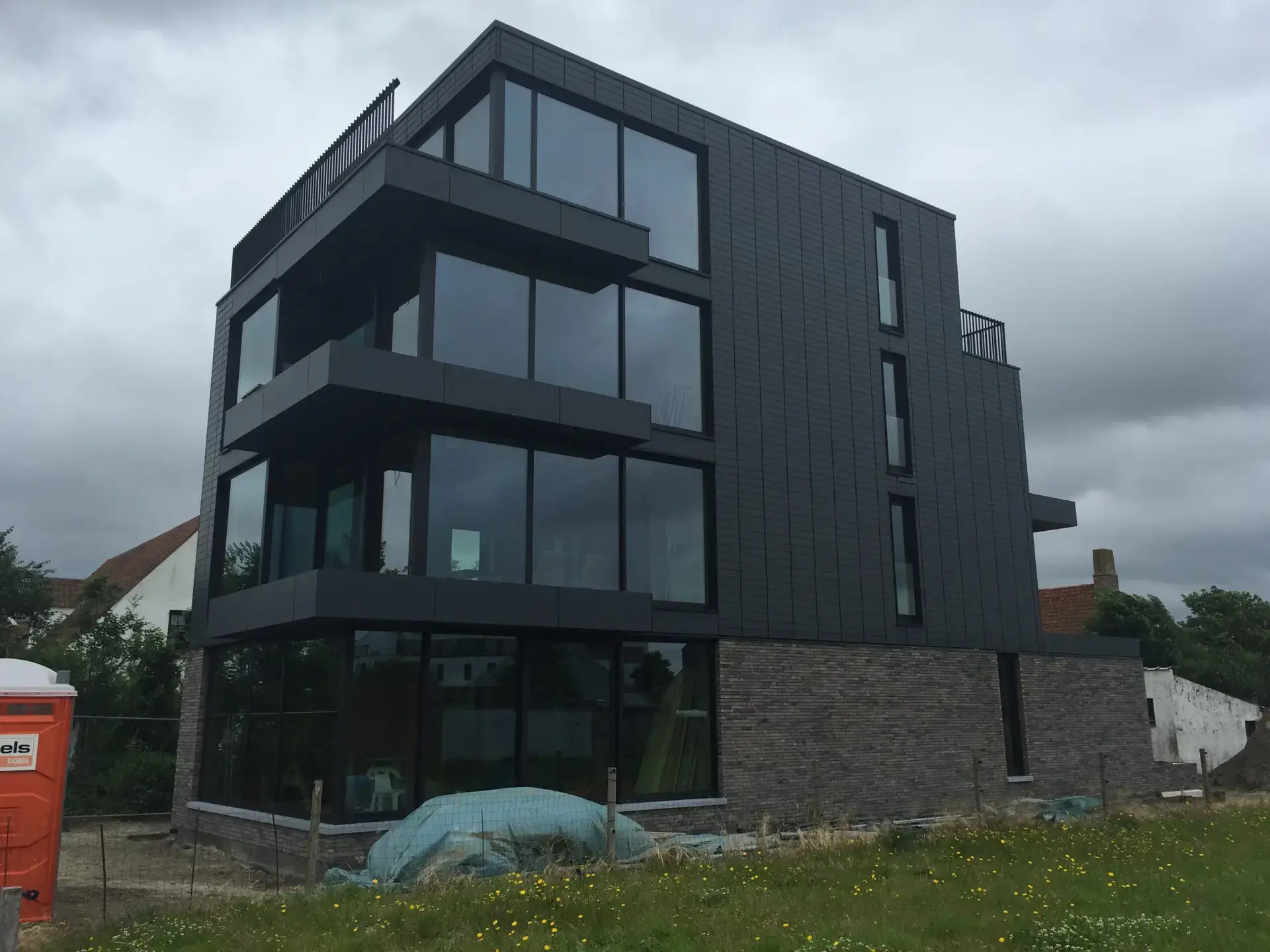 Appartementsgebouw in houtskeletbouw aan de Belgische kust met donkere gevel en grote ramen