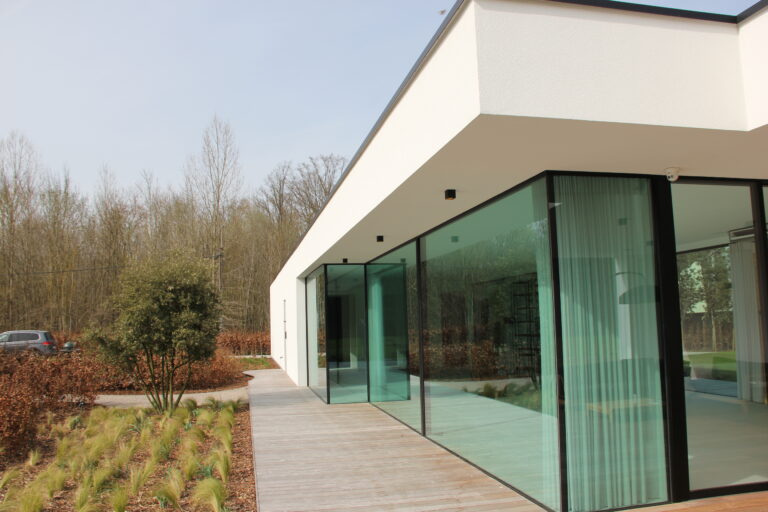 modern architecture met veel glas, crepi en een bankirai pad tussen de aangelegde tuin