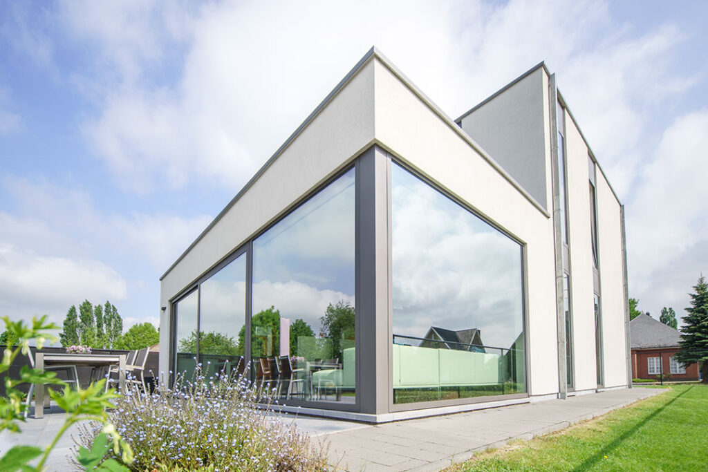 moderne houtskeletbouw met veel glas en plat dak. gevelafwerking in crepi.