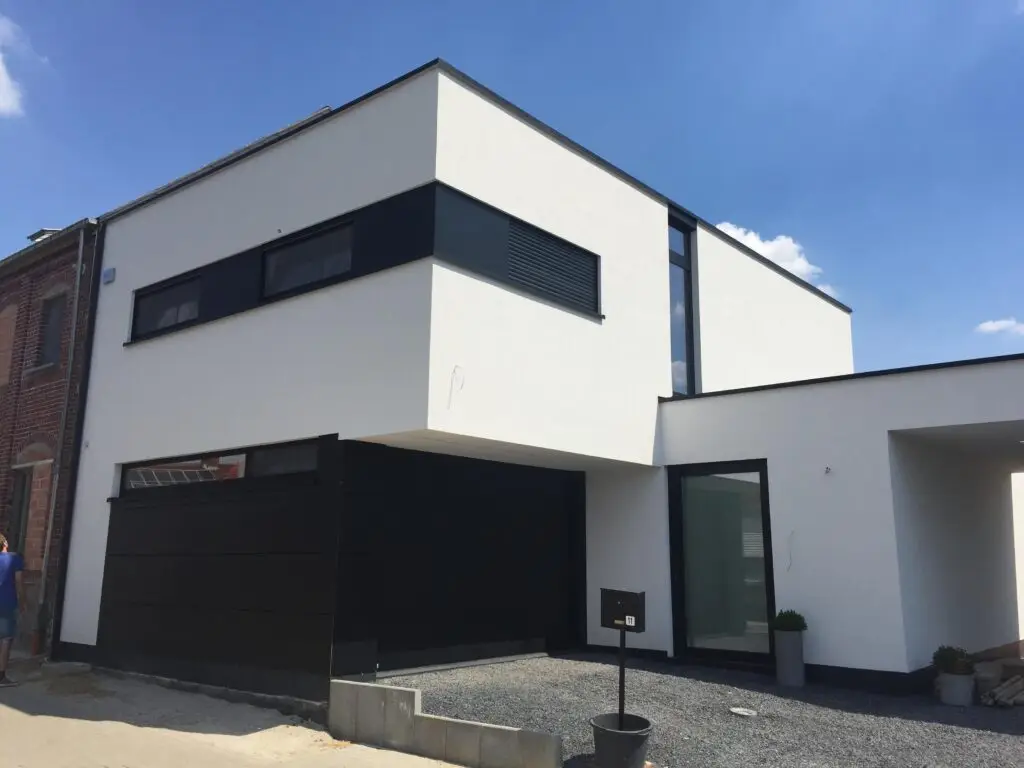 Voorgevel in witte crepi met donkere Trespa-accenten en garage aan de woning in Heldergem
