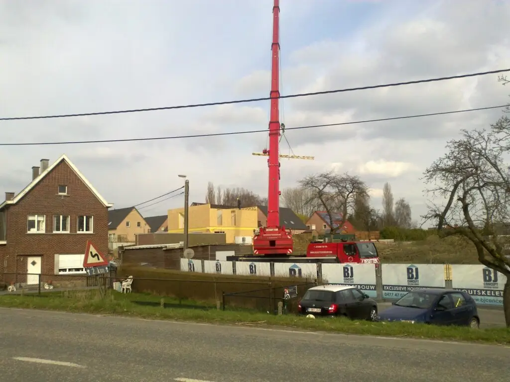 Rode kraan naast de houtskeletwoning in aanbouw in Ophasselt
