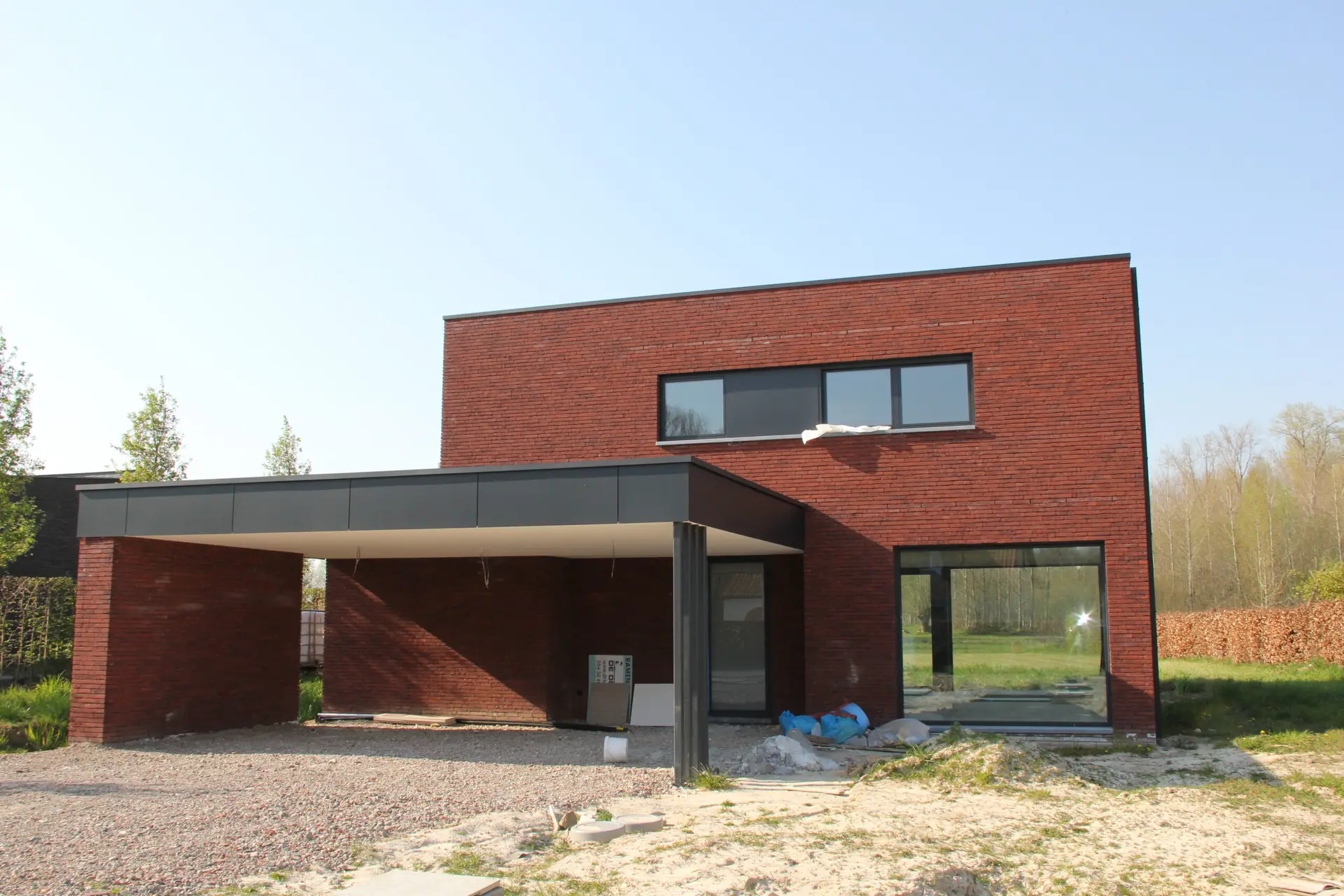 Moderne houtskeletnieuwbouw met rode gevelsteen, donkere panelen en grote ramen
