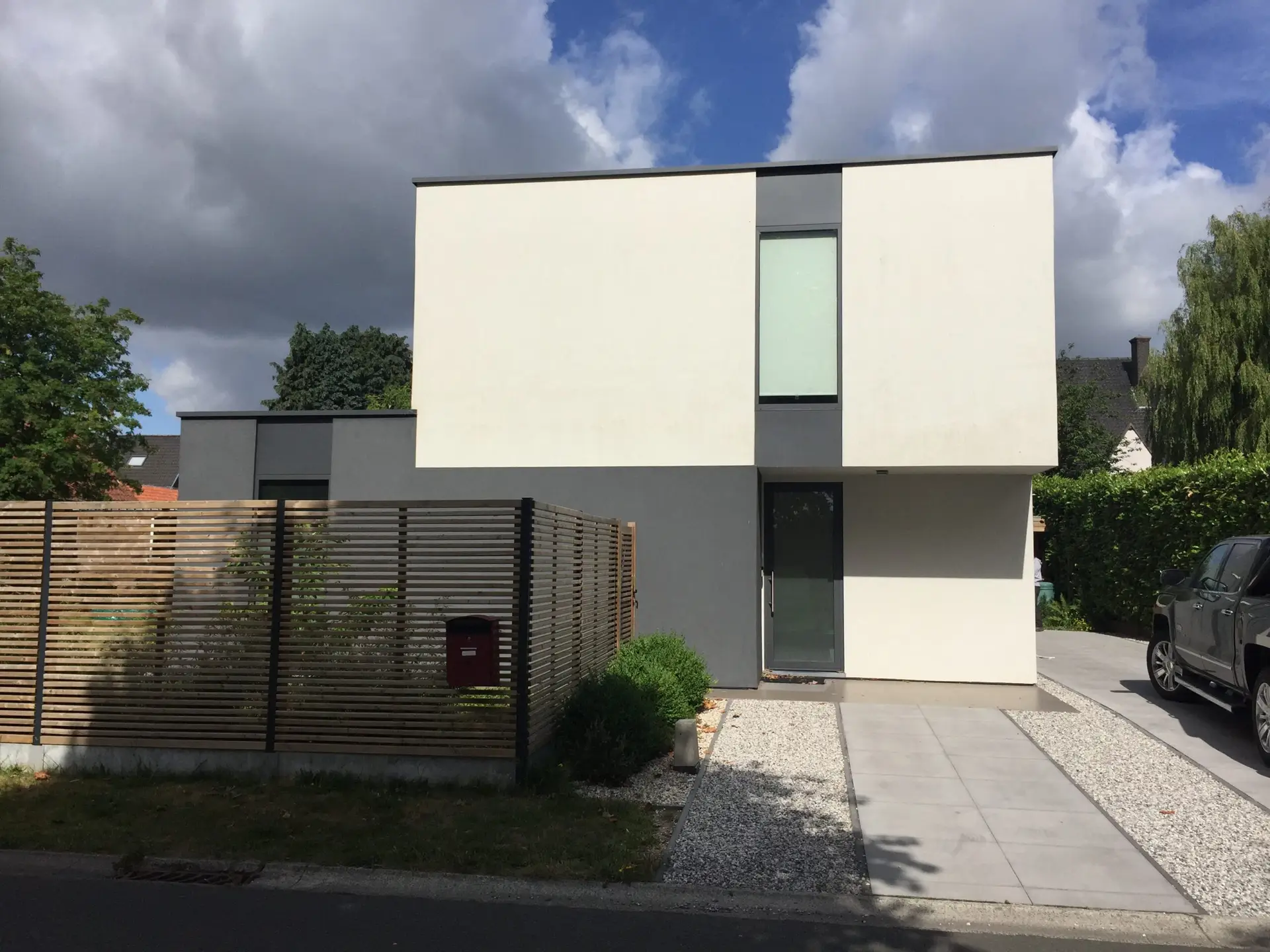 Voorgevel met witte crepi en plat dak van de nieuwbouwwoning in Landegem