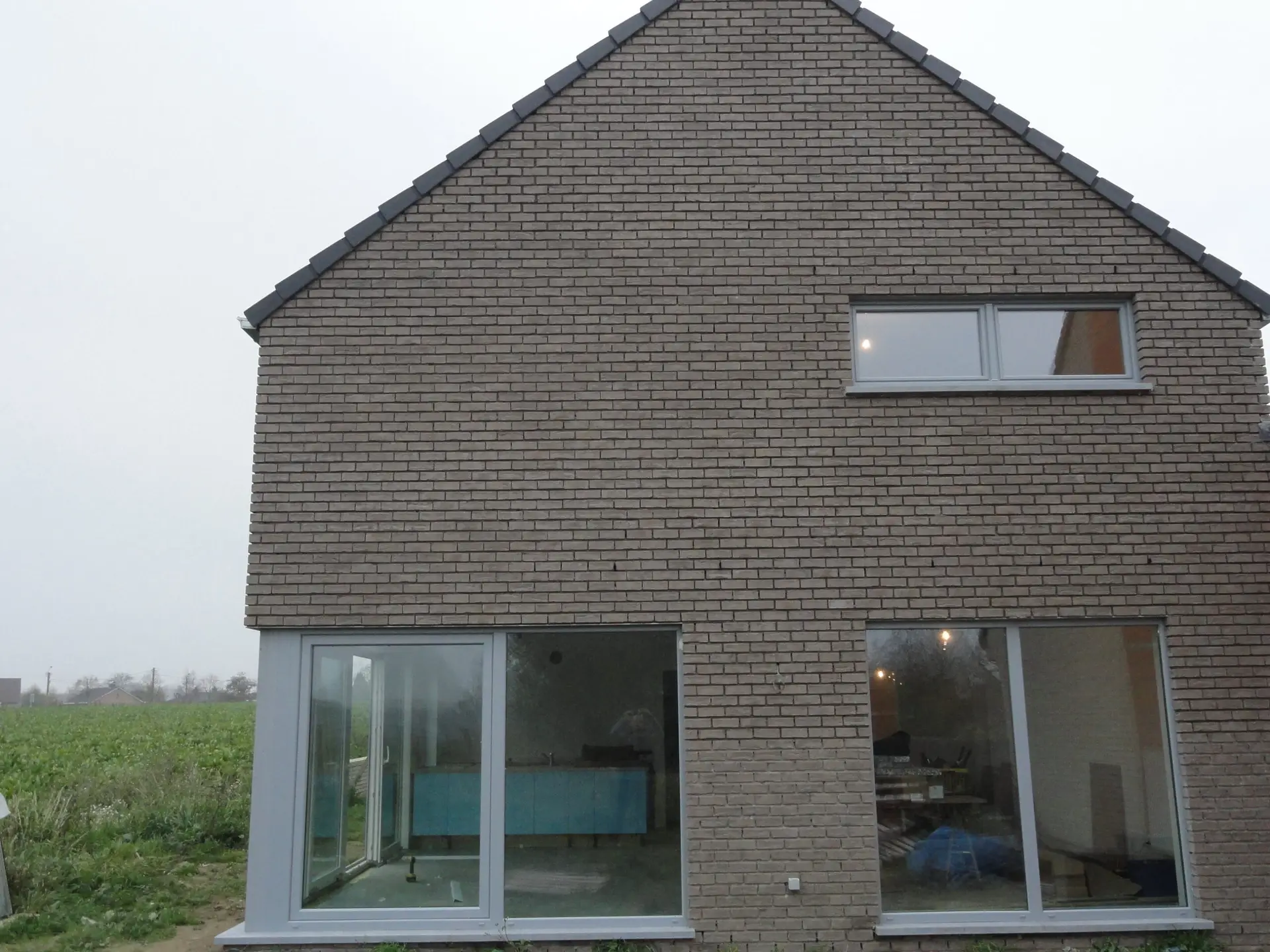 Bakstenen gevel met grote ramen van de nieuwbouwwoning in Diksmuide