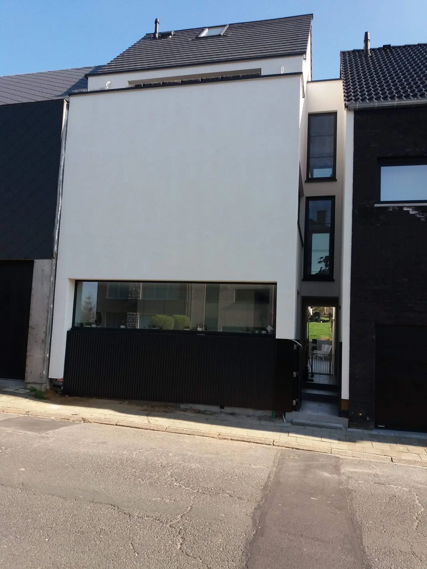 Gevel met lichte crepi en donkere geveldelen van de nieuwbouw in Halle