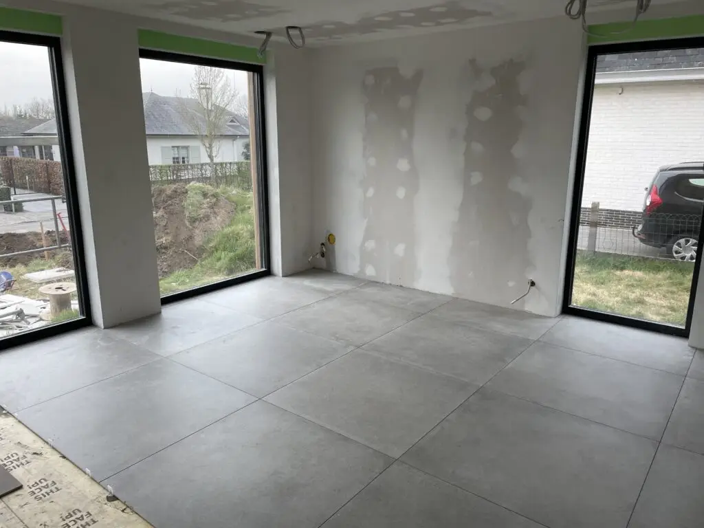 Plaatsing van vloertegels bij schilderklare wanden in de houtskeletwoning in Merelbeke