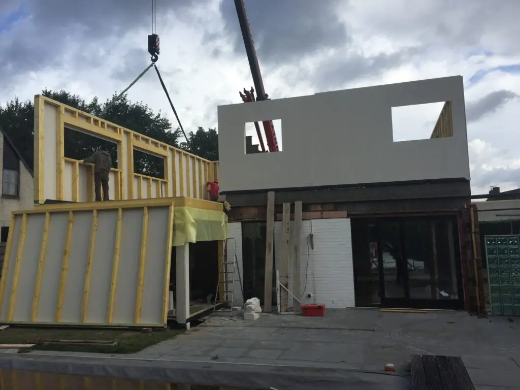 Kraan bij de montage van prefab houtskeletwanden op de woning in Mariakerke