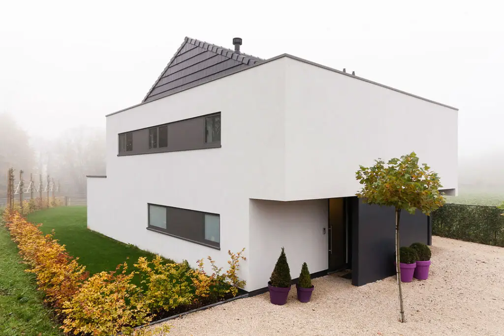 Afgewerkte wellnessvilla in houtskeletbouw in Dilbeek met witte crepi en aangelegde voortuin
