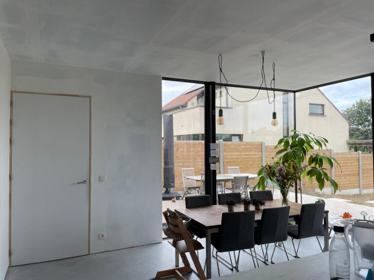 Schilderklare binnen afwerking van de aanbouw in houtskelet. In de keuken staat een tafel met stoelen.