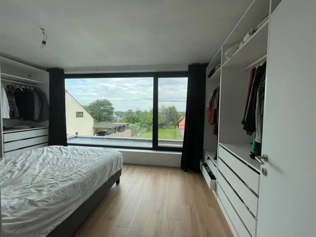 Slaapkamer met open kledingkasten en breed raam in Semmerzake