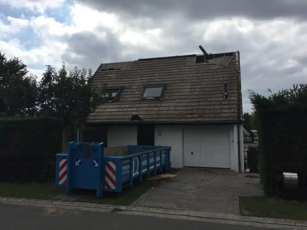 Bestaande woning met deels ontmanteld zadeldak en werfcontainer in Mariakerke