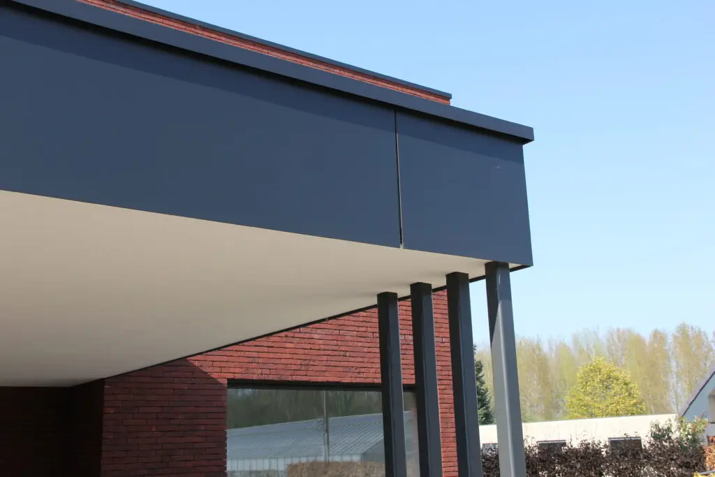 Detail van donkere Trespa-gevelpanelen aan de overstek van een moderne houtskeletnieuwbouw