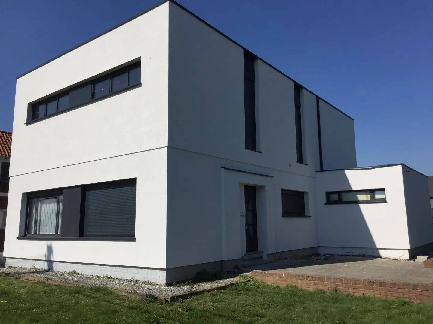 Woning in Oosterzele na de optopping, met een extra verdieping, lichte crepi en donkere ramen