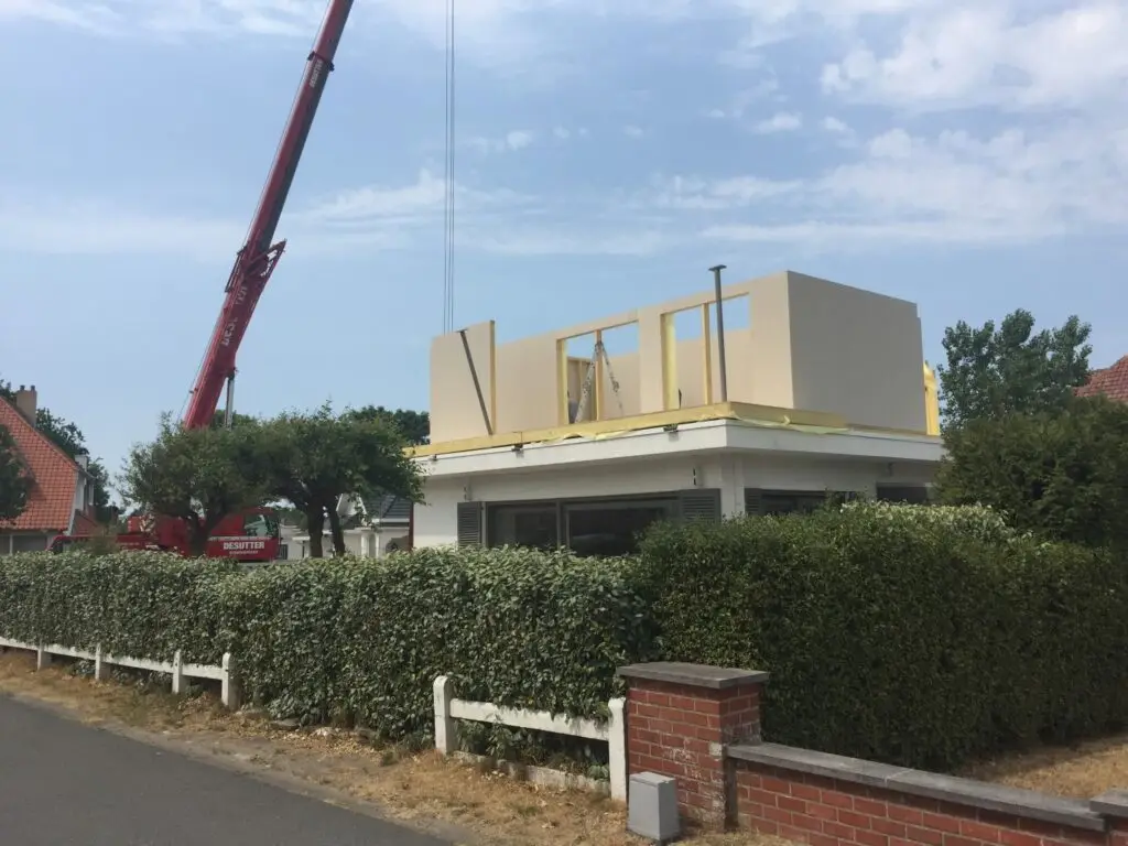 Plaatsing van een houtskeletwand met een kraan op de bestaande woning in Koksijde