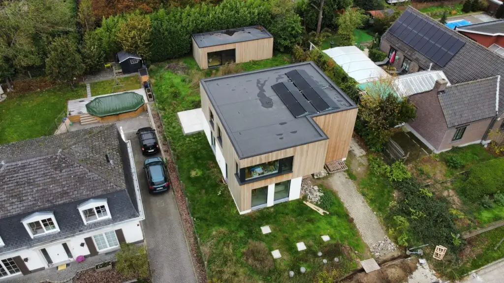 Dronebeeld van de voorgevel en platte daken van de gerenoveerde woning in Merelbeke